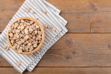 Kuru çiğ cicerchia ya da ahşap bir kasede doğal ahşap arka planda peçeteyle Hint bezelyesi, üst manzara, kopyalama alanı. Lathyrus Sativus olarak bilinen Legumes, Chickling Vetch, Blue Sweet Pea, Puglia 'da üretildi.