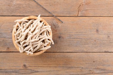 Tahta masadaki bir kasede tam tahıllı apulian makarnası Pizzarieddi veya maccaruni. Taze Maccheroni tipik Puglia Salento İtalya yemeği. İtalyan ev yapımı makarna arka planı, yakın plan, üst manzara
