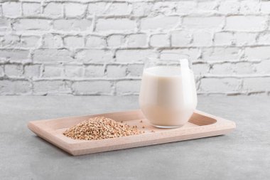 Günlük olmayan vejetaryen karabuğday sütü, tahta bir tabakta, karabuğday filizleri de gri bir taş masada. Vegan karabuğday içeceği, bitki bazlı alternatif süttür. Sebzeler sağlıklı süt ürünü