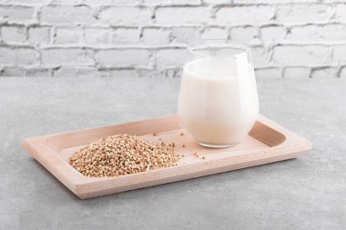 Günlük olmayan vejetaryen karabuğday sütü, tahta bir tabakta, karabuğday filizleri de gri bir taş masada. Vegan karabuğday içeceği, bitki bazlı alternatif süttür. Sebzeler sağlıklı süt ürünü