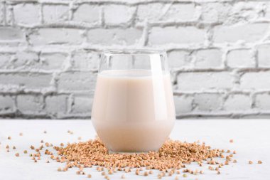 Vejetaryen günlük olmayan karabuğday sütü ve beyaz taş bir masada karabuğday filizleri. Vegan karabuğday içeceği, bitki bazlı alternatif süttür. Sebzeler sağlıklı süt ürünleri, kapatın.