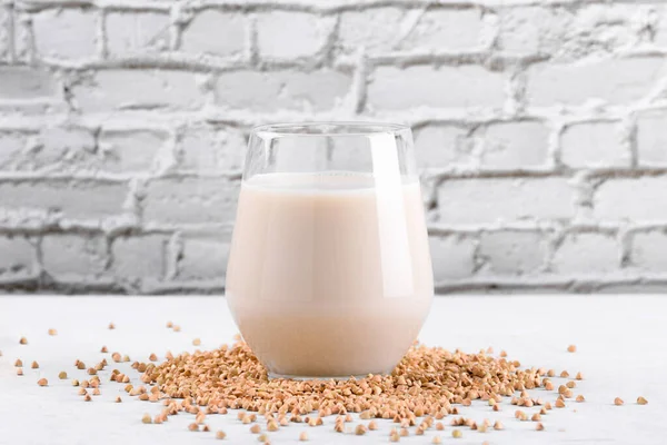 Vejetaryen günlük olmayan karabuğday sütü ve beyaz taş bir masada karabuğday filizleri. Vegan karabuğday içeceği, bitki bazlı alternatif süttür. Sebzeler sağlıklı süt ürünleri, kapatın.