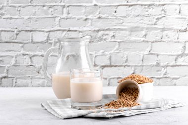 Vejetaryen günlük olmayan karabuğday sütü ve karabuğdaylı bardak beyaz taş bir masada bir kase inliyor. Vegan karabuğday içeceği, bitki bazlı alternatif süttür. Sebzeler sürahide sağlıklı süt ürünü