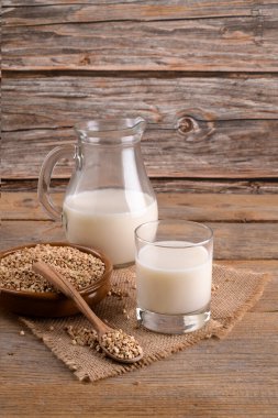 Günlük olmayan vejetaryen karabuğday sütü bardakta ve karabuğday homurdanmaları ahşap arka planda bir klozette. Vegan karabuğday içeceği, bitki bazlı alternatif süttür. Sebzeler sağlıklı süt ürünü