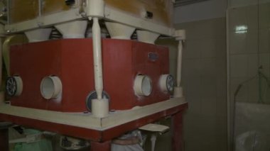 Bir değirmenci mekanik sanayi fabrikasının işleyişini kontrol eder, un çuvalını düzeltir, yeni öğütülmüş un çuvala dökülür. Puglia, İtal