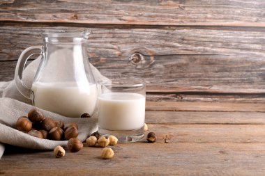 Vejetaryen fındıklı süt bardakta ve fındıklı sütü kırsal ahşap arka planda keten peçetede. Laktoz içermeyen fındık suyu, bitki bazlı alternatif süttür. Sağlıklı süt ürünü