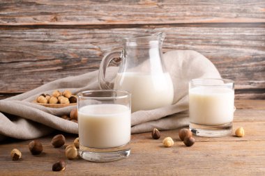 Vejetaryen fındıklı süt bardakta ve fındıklı sütü kırsal ahşap arka planda keten peçetede. Laktoz içermeyen fındık suyu, bitki bazlı alternatif süttür. Sağlıklı süt ürünü