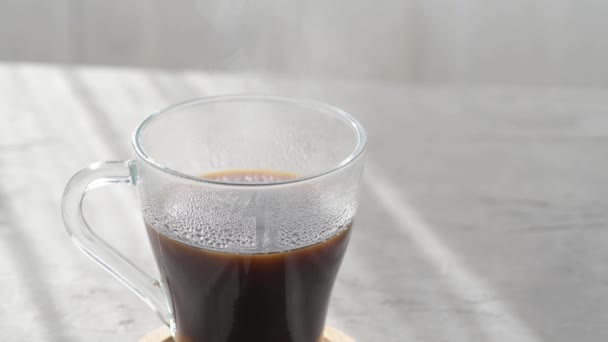 在灰色桌子背景的晨影下蒸煮热咖啡杯 热的透明玻璃杯 带有蒸汽的灰色桌子背景 热咖啡饮料概念 — 图库视频影像