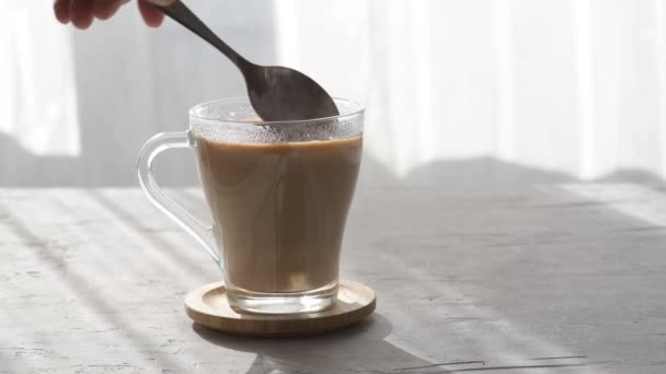 糖从勺子里倒入透明的咖啡杯里 里面装着牛奶和晨光 勺子在咖啡杯里加了糖 是在搅拌杯子里的糖 — 图库视频影像