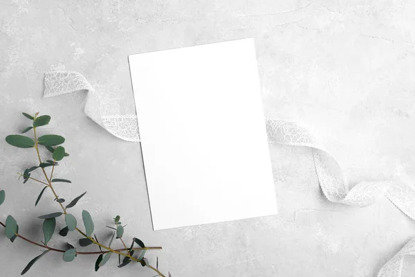 Wedding stationery invitation cards mockup 5x7 on neutral grey stone background with eucalyptus leaves