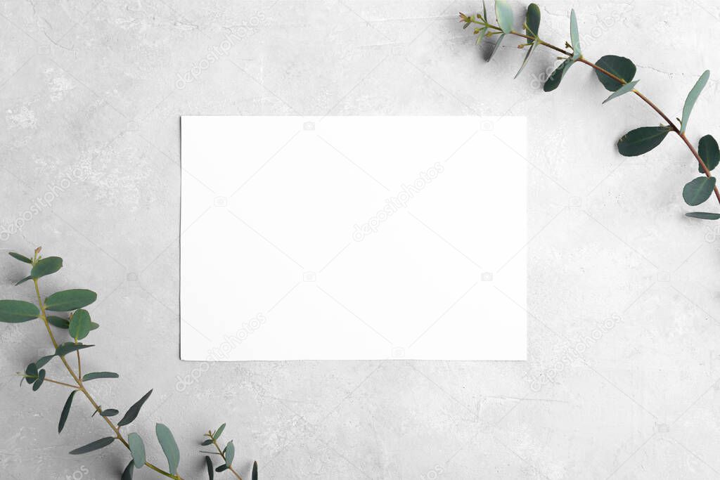Wedding stationery landscape invitation card mockup 5x7 on neutral grey stone background with eucalyptus leaves