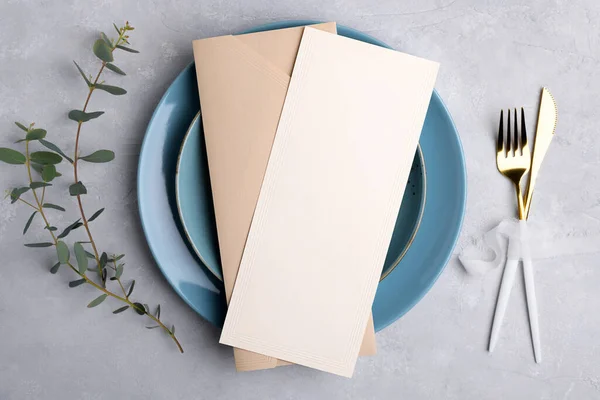 Menu card mockup with envelope on blue plate with festive table setting with eucalyptus branch on grey background — стоковое фото