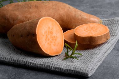 Çiğ portakallı tatlı patates ve gri beton arka planda taze biberiye dilimleri, üst manzara, kopyalama alanı, düz yatış