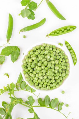 Beyaz arka planda bezelye kabukları ve bitkilerle bezelye kabuğundaki taze organik taze taze bezelyeler. Sağlıklı beslenme, vegan ve vejetaryen baklagil yiyeceği, çiğ yemek ve detoks süper yemek, fasulye proteini, üst görünüm