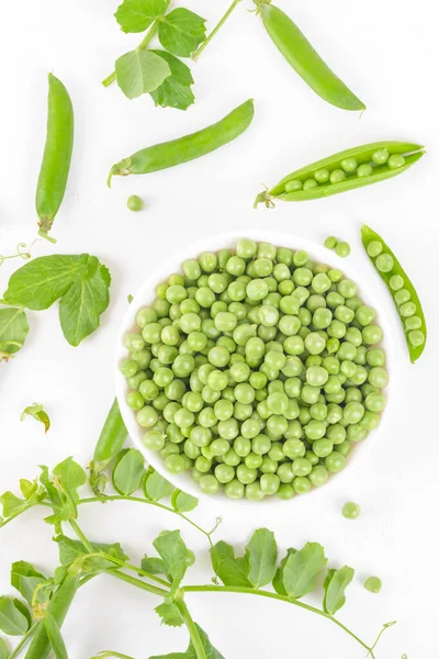 Beyaz arka planda bezelye kabukları ve bitkilerle bezelye kabuğundaki taze organik taze taze bezelyeler. Sağlıklı beslenme, vegan ve vejetaryen baklagil yiyeceği, çiğ yemek ve detoks süper yemek, fasulye proteini, üst görünüm