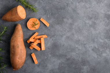 Çiğ portakallı tatlı patates ve gri beton arka planda taze biberiye dilimleri, üst manzara, kopyalama alanı, besin düzlemi