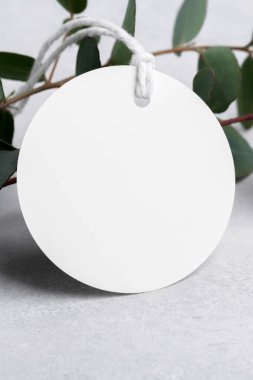 Gri arkaplanda okaliptüs yaprakları olan yuvarlak beyaz hediye etiketi modeli, etiket modeli, hatıra için düğün hediyesi etiketi, tebrik mesajı için imza, tasarım için element, kapat