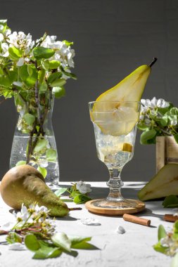 Armut kokteyli, armut püresi, taze meyve ve açık gri arka planda çiçekler. Yaz aylarında soğuk armut, masada buzlu limonata, çiçekli dallı köpüklü Mocktail tatlı içeceği.