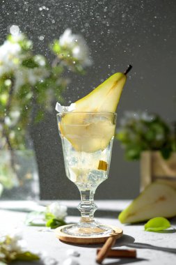 Armut kokteyli, armut püresi, taze meyve ve açık gri arka planda çiçekler. Yaz aylarında soğuk armut, masada buzlu limonata, çiçekli dallı köpüklü Mocktail tatlı içeceği.