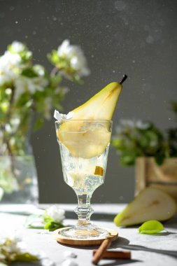 Armut kokteyli, armut püresi, taze meyve ve açık gri arka planda çiçekler. Yaz aylarında soğuk armut, masada buzlu limonata, çiçekli dallı köpüklü Mocktail tatlı içeceği.