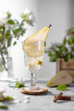 Armut kokteyli, armut püresi, taze meyve ve açık gri arka planda çiçekler. Yaz aylarında soğuk armut, masada buzlu limonata, çiçekli dallı köpüklü Mocktail tatlı içeceği.
