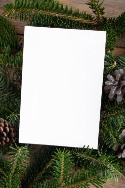 Noel 5x7 kart modelleme şablonu ahşap arka plandaki doğal köknar dalları üzerinde. Noel ve Yeni Yıl için tasarım öğesi, tebrik, cevap, teşekkür ederim, selamlama veya davetiye kartı, satış