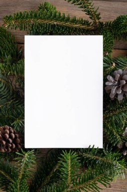 Noel 5x7 kart modelleme şablonu ahşap arka plandaki doğal köknar dalları üzerinde. Noel ve Yeni Yıl için tasarım öğesi, tebrik, cevap, teşekkür ederim, selamlama veya davetiye kartı, satış