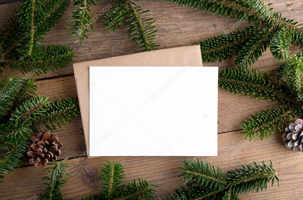 Christmas 7x5 card mockup template with envelope with fir twigs and Christmas decor on wooden background. Design element for Christmas and New Year congratulation, greeting or invitation card