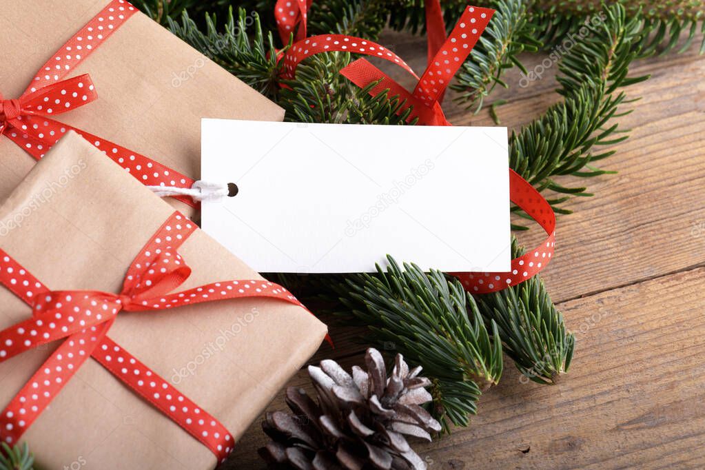 Christmas rectangle gift tag mockup with present box, product label mockup, with natural fir tree branch, cones and Christmas decoration, Christmas sale concept. Blank paper rectangular name tag