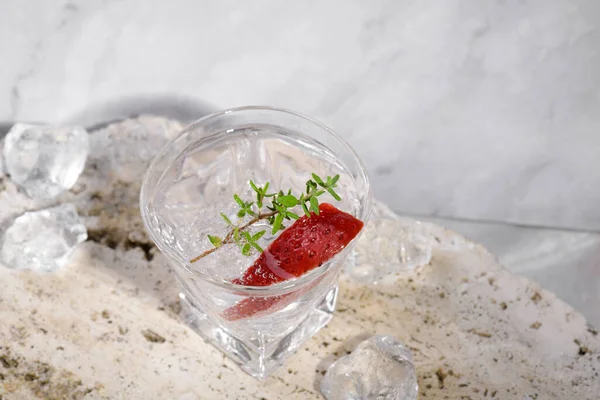 Vodka Shot Glass Ice Decorated Strawberry Slice Thyme Travertine Podium — Stock Photo, Image