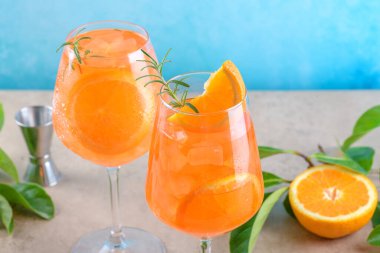 Classic italian aperitif aperol spritz cocktail in two wineglasses with ice cubes and slice of orange with light blue background on beige stone background, traditional summer fresh iced drink, closeup
