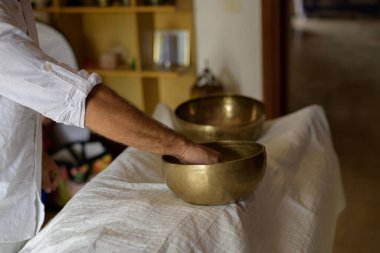 Tibetli şarkı kasesi ustası Nepal Buddha şarkı kasesiyle evde ses masajı yapıyor. Beyazların çalışma terapisi, seçici odaklanma.