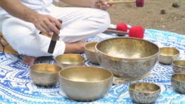 Erkek ellerinin şarkı söyleyen Tibet kâselerinde oynadığı ve içinde manikür padme mırıltısının yazıldığı yakın plan. Meditasyon, rahatlama, yoga için müzik aletleri.