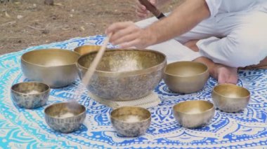 Erkek ellerinin şarkı söyleyen Tibet kâselerinde oynadığı ve içinde manikür padme mırıltısının yazıldığı yakın plan. Meditasyon, rahatlama, yoga için müzik aletleri.