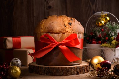 Geleneksel İtalyan Noel Keki Panettone, kırmızı yaylı ve ahşap arka planda şenlikli. Ev yapımı ekşi mayalı panettone klasik İtalyan Noel Yemeği ve Yenilebilir Hediye 'sidir.