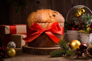 Geleneksel İtalyan Noel Keki Panettone, kırmızı yaylı ve ahşap arka planda şenlikli. Ev yapımı ekşi mayalı panettone klasik İtalyan Noel Yemeği ve Yenilebilir Hediye 'sidir.