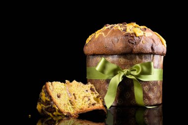 Geleneksel İtalyan Noel Pastası Panettone, yeşil fiyonklu ve siyah arka planda izole edilmiş bir pasta dilimi. Ev yapımı ekşi mayalı panettone klasik İtalyan Noel Yemeği Yenilebilir Hediye