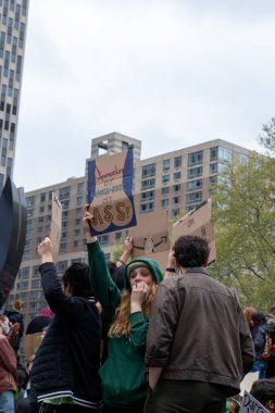 A young Female holding a cardboard sign with the words 