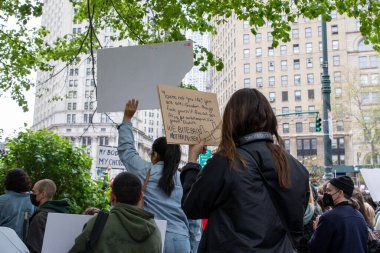 A young female holding a cardboard sign with the words 