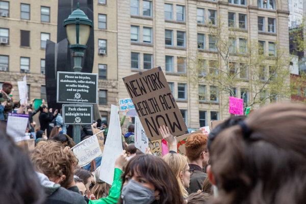 Молодая женщина, держащая картонный знак со словами "Нью-Йоркский закон о здоровье", написанный на нем на площади Фоли, Нью-Йорк, США 05-03-2022 Протестующие держат плакаты