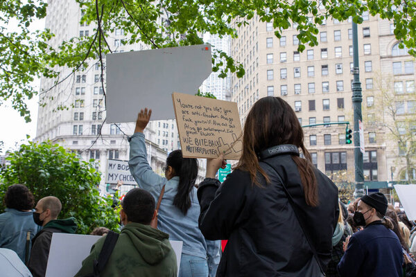 A young female holding a cardboard sign with the words "You're not "pro-life". you are anti-freedom. also, go fuck yourself. also. eat shit. also, get curb stomped. eat gravel. we bite back motherfuckerl " written on it at Foley Square, New York, NY,