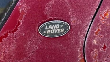 İngiliz şirketi Land Rover 'ın kırmızı arabadaki logosu kışın ayazla kaplıdır.