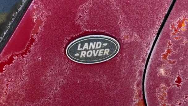 British company Land Rover logo on a red car is covered with frost in winter — Video Stock
