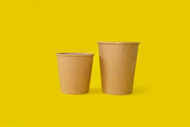 Parlak sarı arka planda iki kağıt bardak.