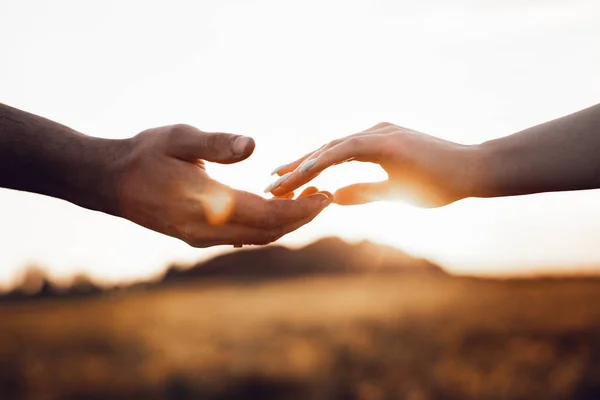 Young married couple touches each other\'s hands. Photo of hands on sky background. Photo with light noise