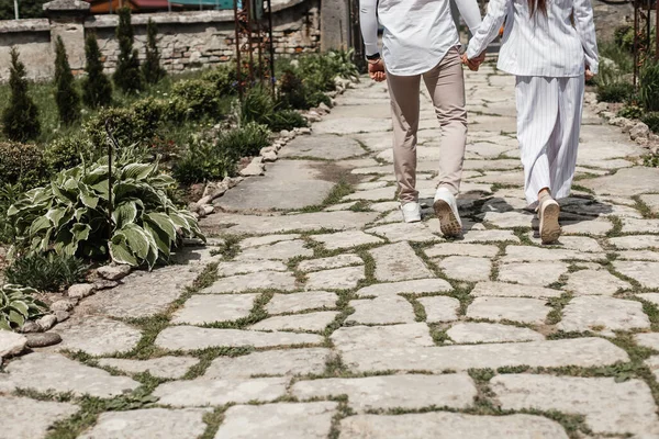 Birbirine aşık bir çift, taş döşeli bir yolda el ele yürür. Arkaplan için metin için alanı olan çiftin arka plan fotoğrafı