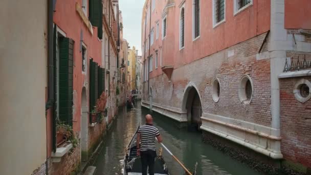 Gondol gün içinde Venedik, İtalya 'da kanala iniyor. Gondolcu dümenci. Turistler gezintiden ve fotoğraf çekmekten hoşlanırlar. Ortaçağ binaları, kanal suları — Stok video