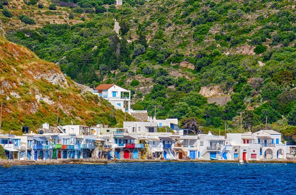 Village of Klima, Milos island, Greece on sunny summer day. Colorful fisherman houses by waterfront, high green hills in background — Stock Photo, Image