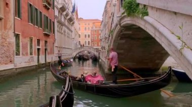 Gondol gün içinde Venedik, İtalya 'da kanala iniyor. Gondolcu dümenci. Turistler gezintiden ve fotoğraf çekmekten hoşlanırlar. Ortaçağ binaları, kanal suları 