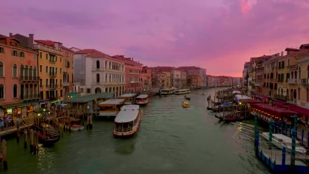 Vista do Grande Canal, Veneza, Itália, filmado a partir da ponte Rialto ou Ponte di Rialto ao pôr do sol. Ônibus aquáticos ou vaporettos, gôndolas, barcos passam — Vídeo de Stock